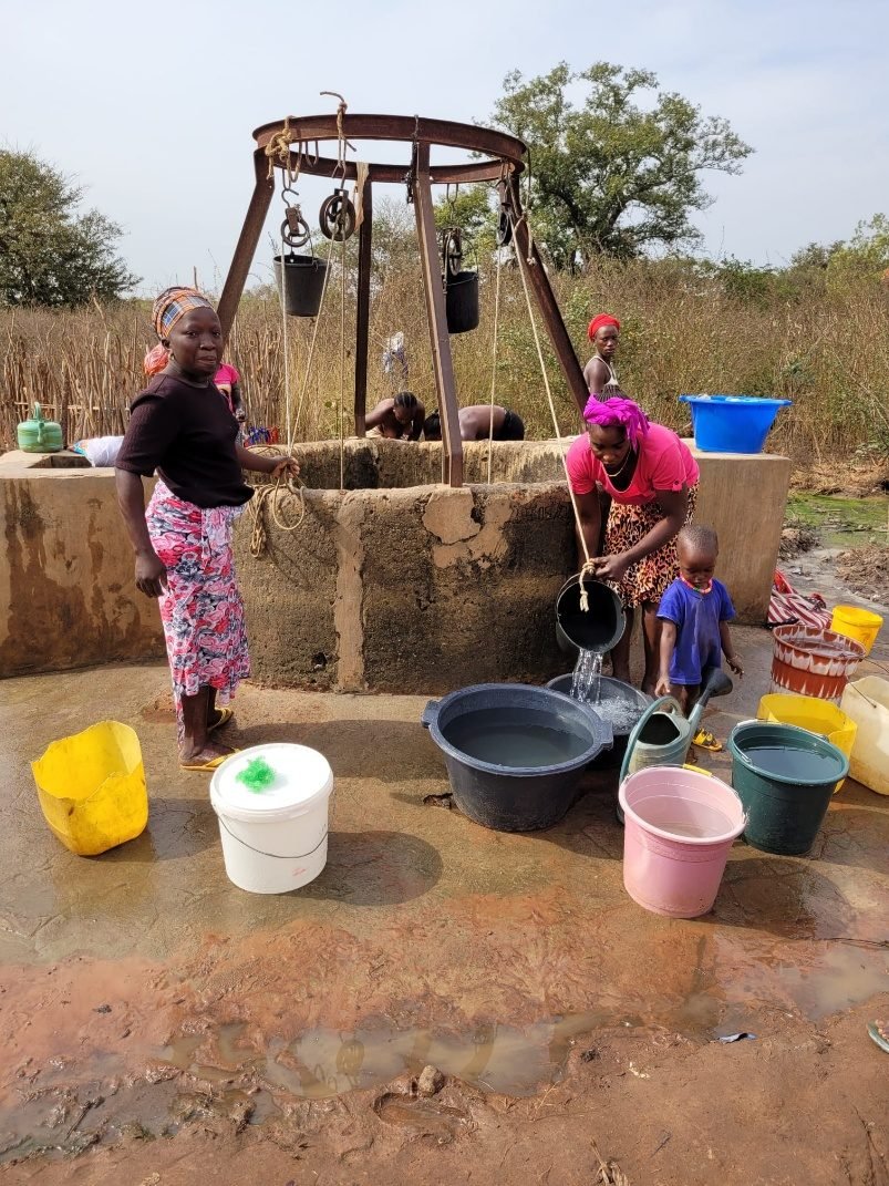 Mujeres y niños recogiendo agua en un pozo de una aldea de Guinea-Bisáu